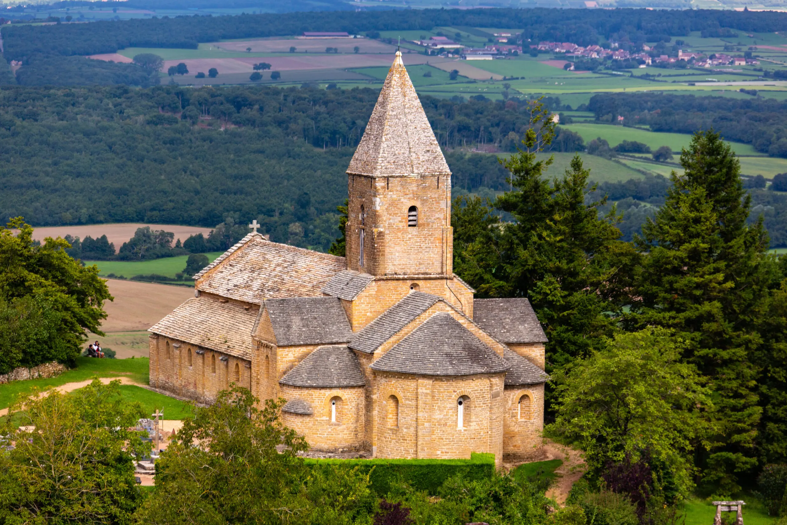 Église Saint-Pierre in Brancion, Burgundy, France Église Saint-Pierre in Brancion, Burgundy, with a pointed stone bell tower overlooking wooded hills and patchwork farmland.