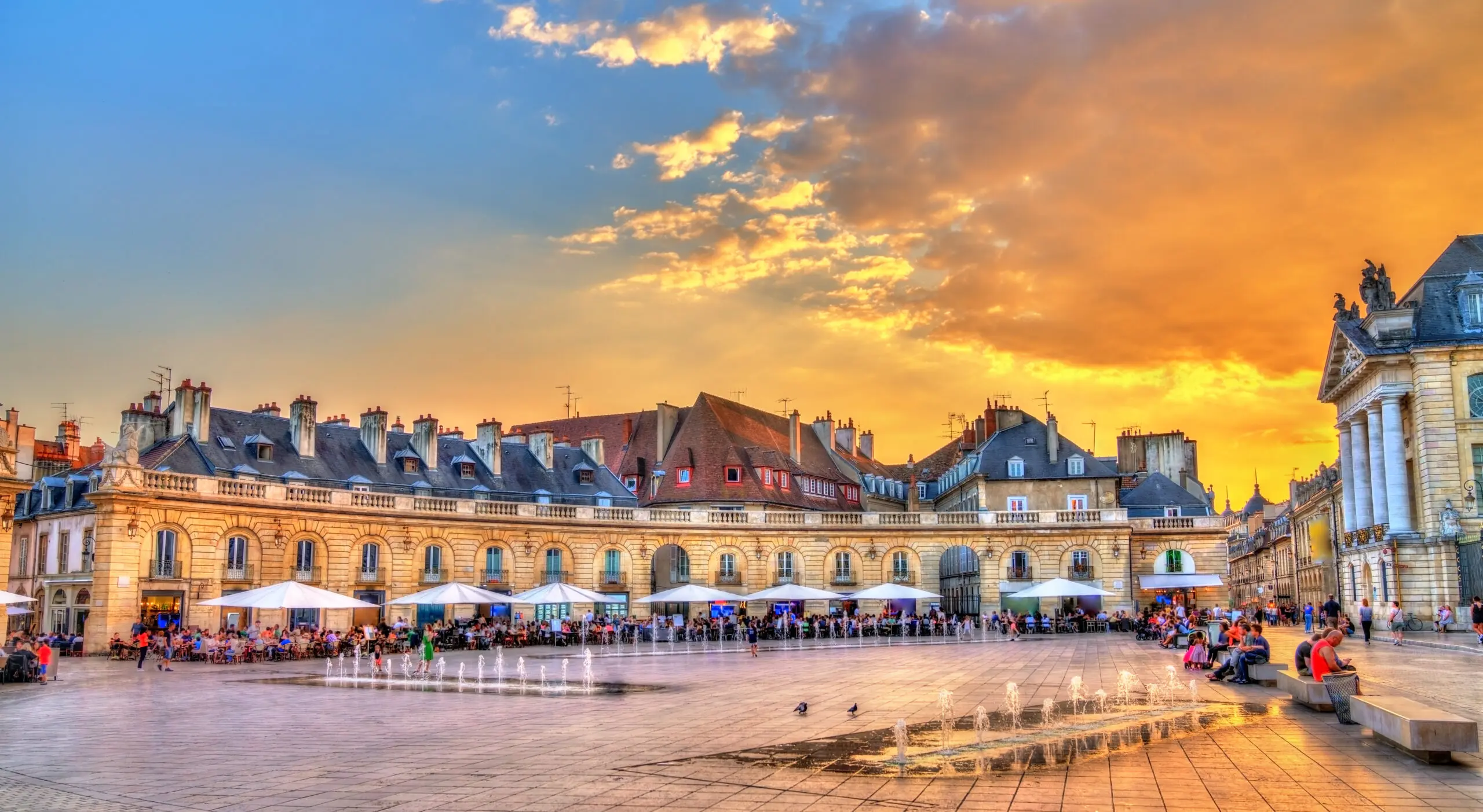 Place de la Libération at Sunset, Dijon, Burgundy Fountains and café terraces in Place de la Libération beside the Palais des Ducs in Dijon beneath a golden sunset sky.