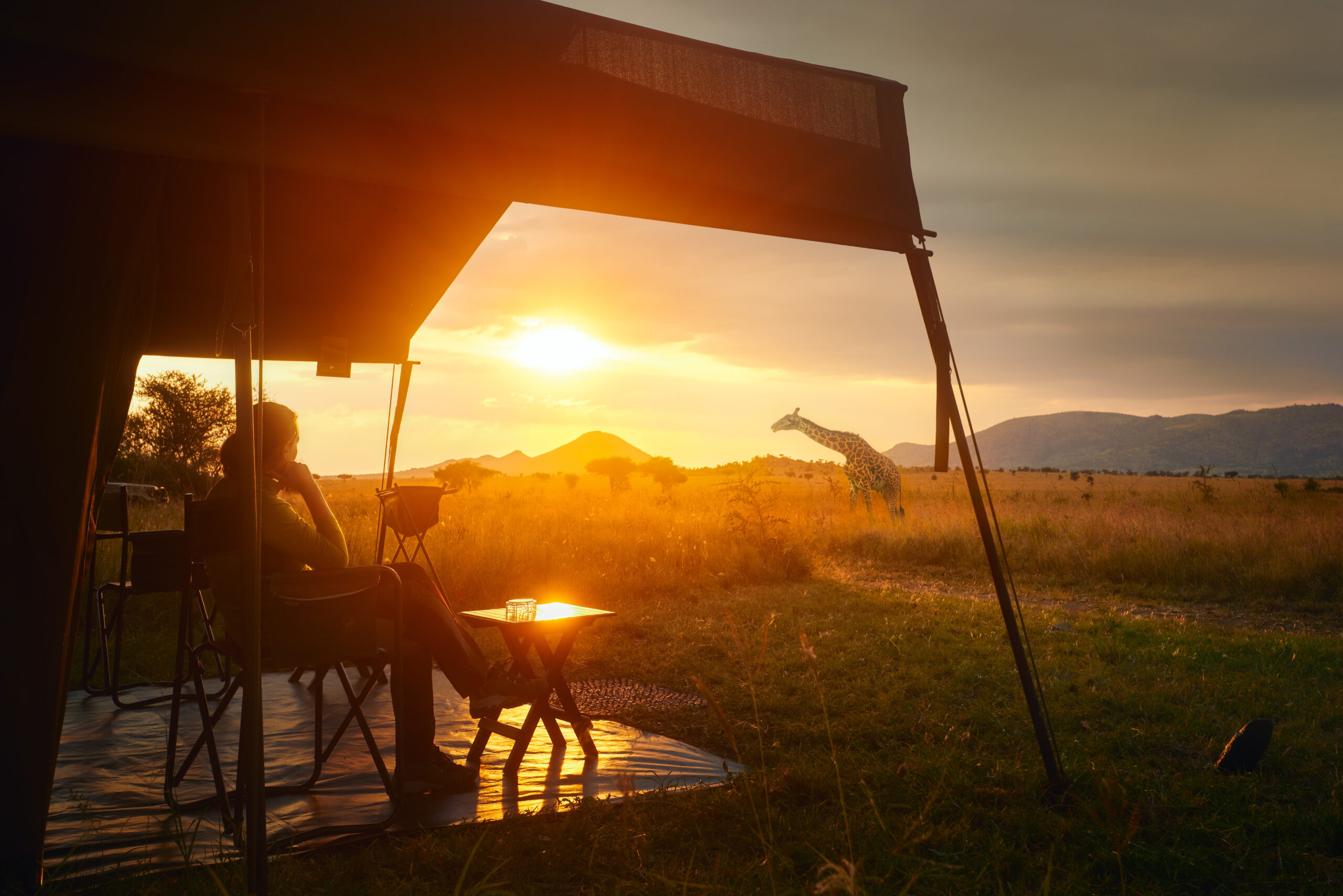 Woman rests after safari in luxury tent during sunset camping in